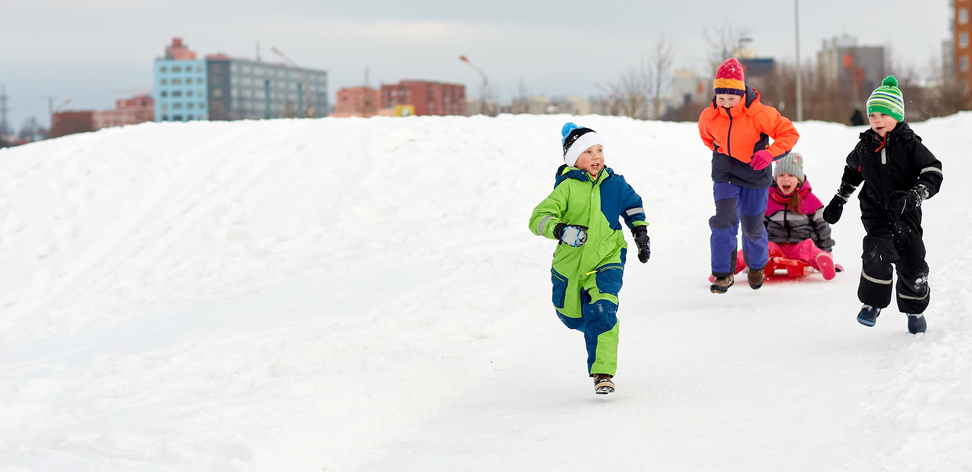 Fyra barn som åker pulka i snön.