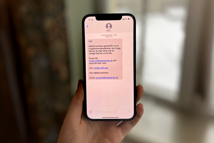 Mobiltelefon med ett sms. Som avsändare står "Mjolby".