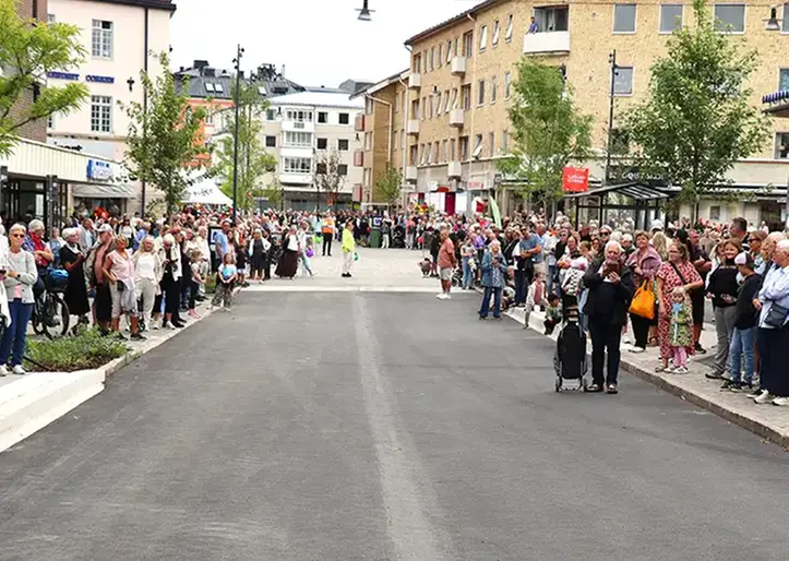Folk som står utmed en tom gata.
