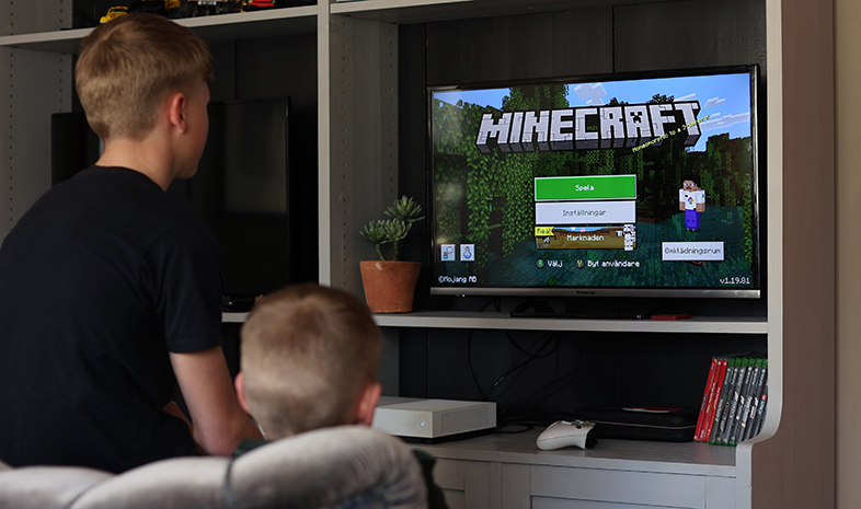 Två barn framför en skärm som spelar Minecraft