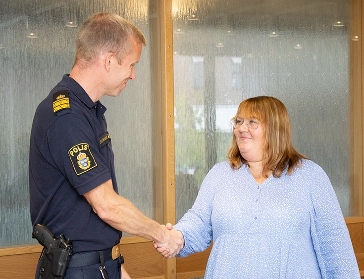 Kommunstyrelsens ordförande skakar hand med polisen i samband med Medborgarlöftet.