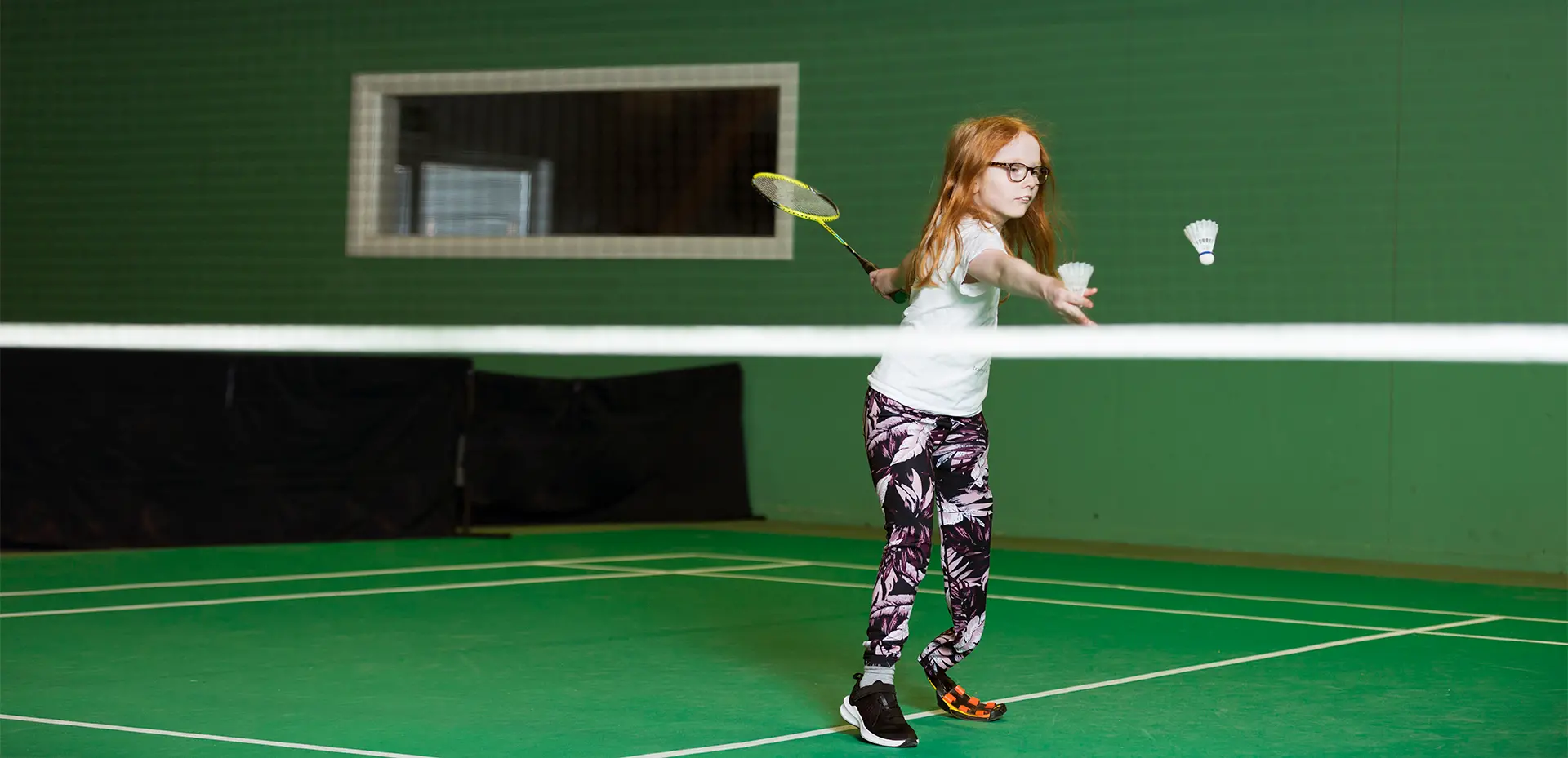 Flicka med fotprotes spelar badminton  