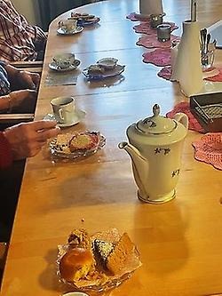Kaffekoppar och kanna i fint gammalt porslin samt kakor på fat..