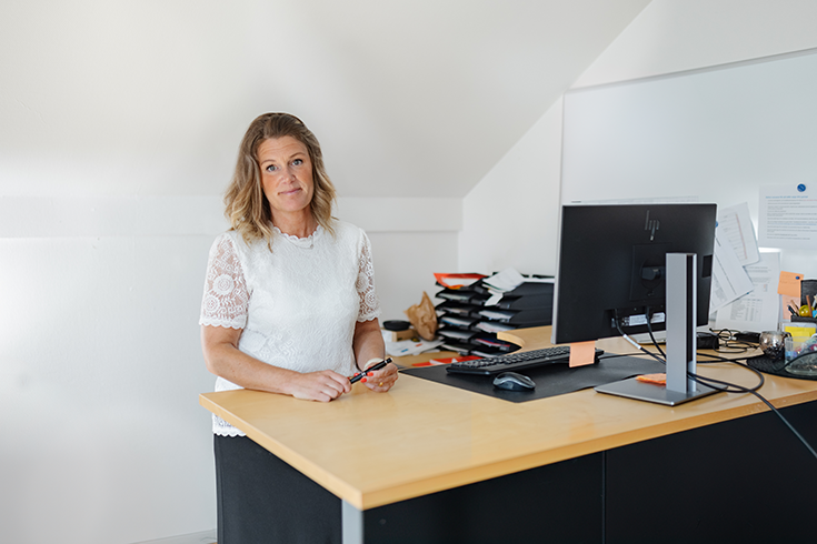 Jennica står intill sitt skrivbord