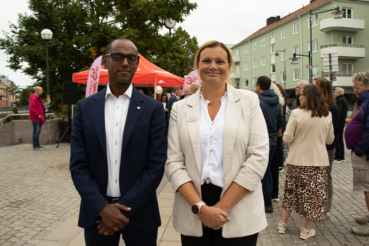 Två personer med minglande människor i bakgrunden.