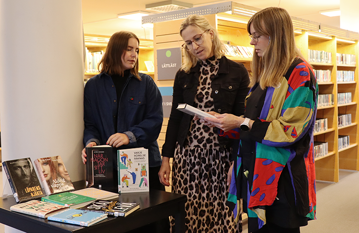 Bibliotekarie Clara Karlin, hållbarhetsstrateg Karin Ulrich och bibliotekarie Anna Hagelin, vid bokbordet i Mjölby bibliotek.