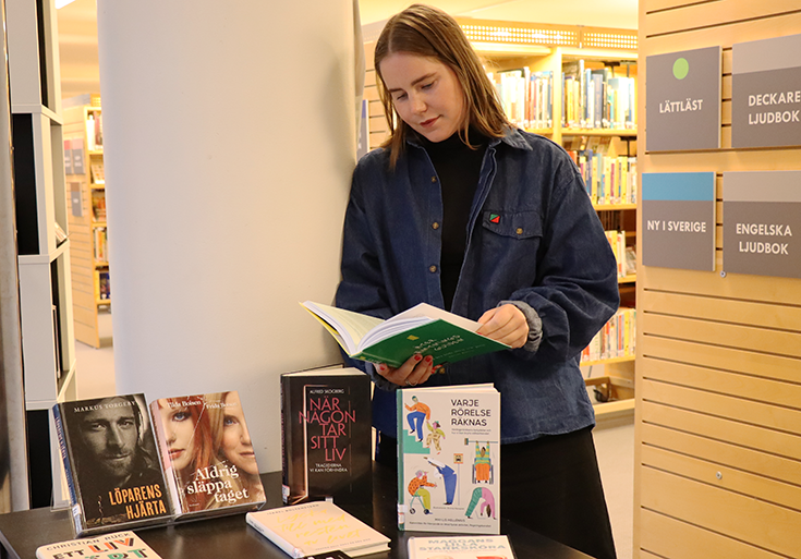 Bibliotekarie Clara Karlin läser i en av böckerna om suicidprevention.