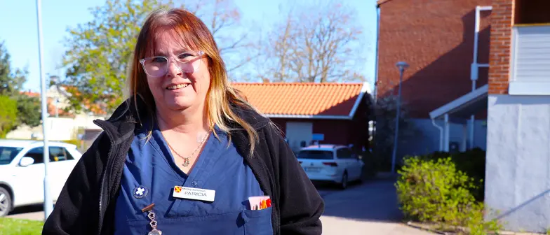 Patricia Axelsson tittar in i kameran och ler. Hon står utomhus framför en parkering.