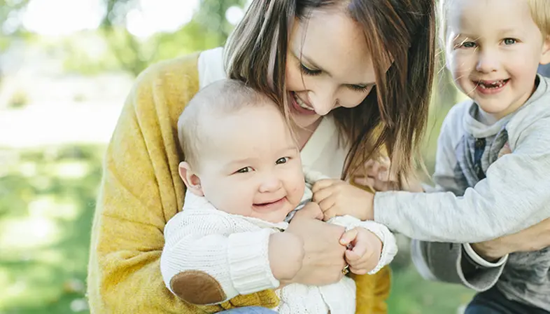 En kvinna håller i sina två barn. 