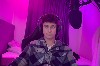 Ung kille framför datorn med mikrofon och hörlurar