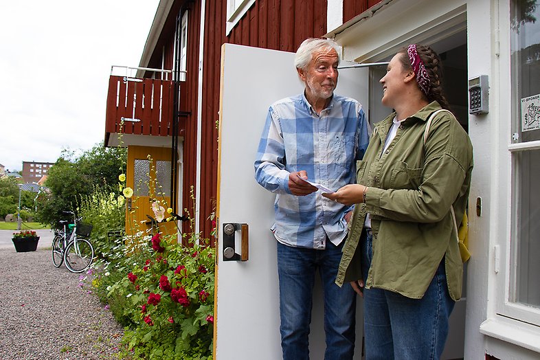 En man och en kvinna framför ett rött hus. 