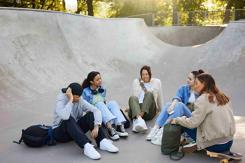 Bild på några ungdomar som siter i en skatepark.