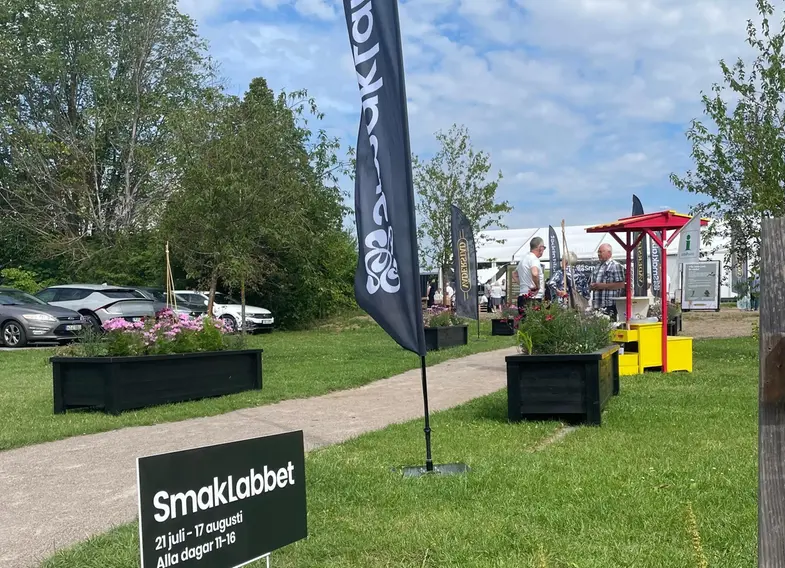 Grusgången upp till eventhallen med blommor och flagga i förgrunden. 