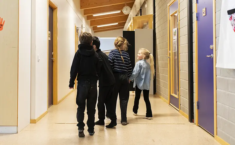 Fyra elever går i en skolkorridor.
