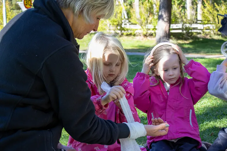 Två barn sätter bandage på sin pedagog. 