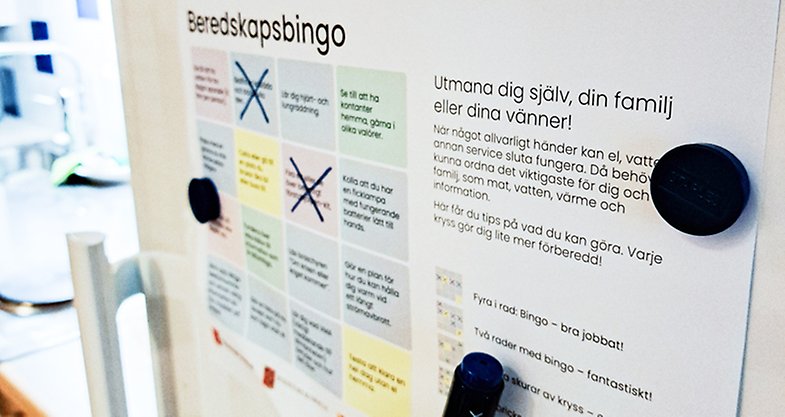 Lapp på kylskåp med texten "Beredskapsbingo" med färgglada bingorutor.