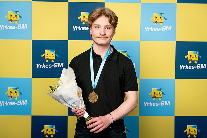 Edvin står med blommor och medalj. 