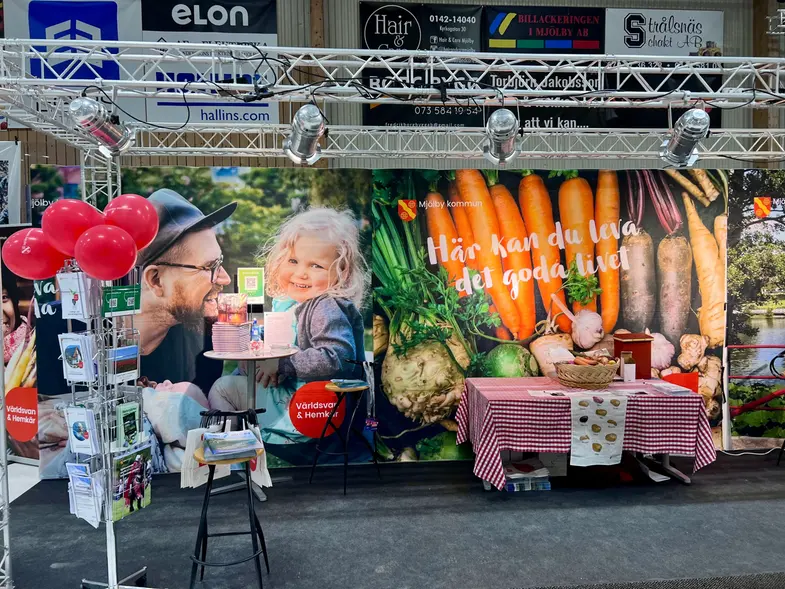 Bilden föreställer Mjölby kommuns monter på förra årets mässa. Montern är fylld med ballonger, broschyrer och har färgglada tygstycken som ramar in. 