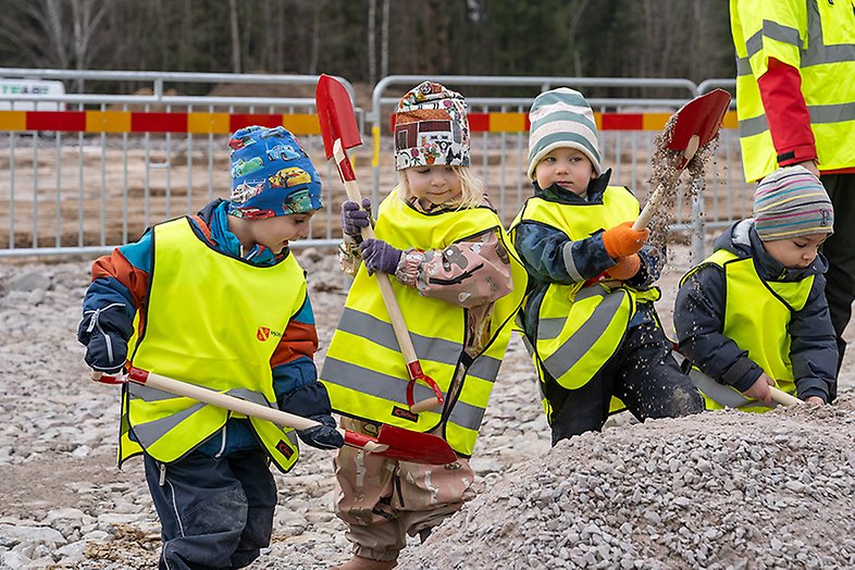 Fyra barn gräver i en grushög. 