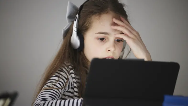 Flicka med hörlurar som tittar på en digital skärm