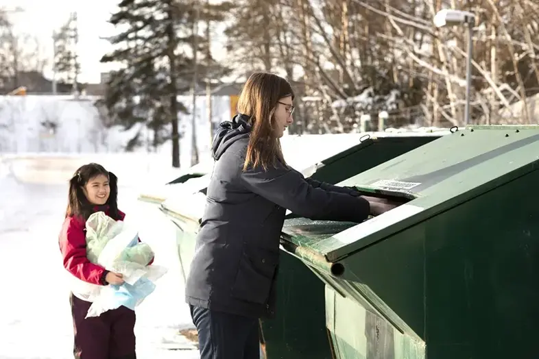 Vuxen och barn slänger förpackningar på återvinningsstation