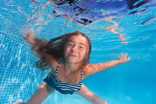Ung tjej simmar under vattnet i en simbassäng