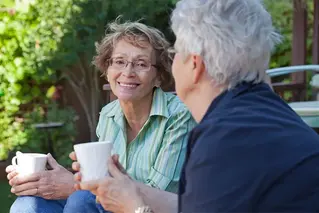 Två äldre kvinnor sitter och pratar med varsin kaffekopp