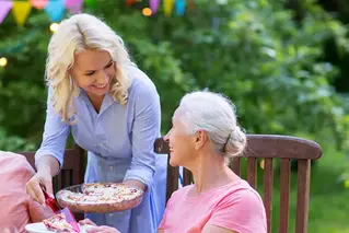 Kvinna serverar en äldre kvinna paj.