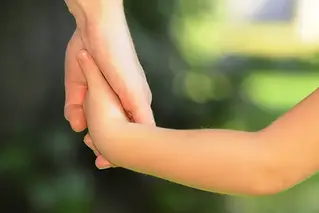En barnhand håller i en vuxenhand.