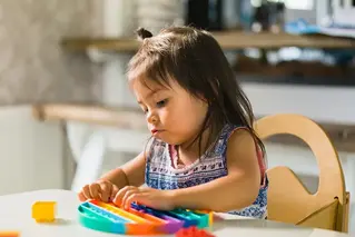 Liten flicka leker med färgglad leksak.