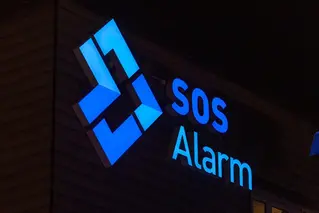 En fasad med en skylt som lyser i blått och med texten SOS Alarm.